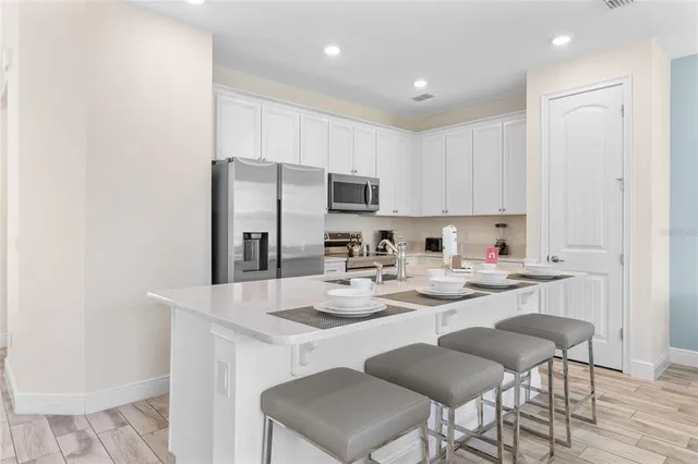 a kitchen with stainless steel appliances granite countertop a white refrigerator a sink a stove a dining table and chairs