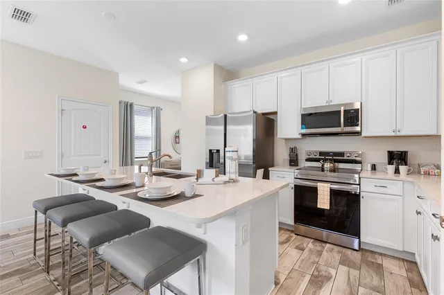 a kitchen with stainless steel appliances kitchen island granite countertop a stove a sink a dining table and chairs