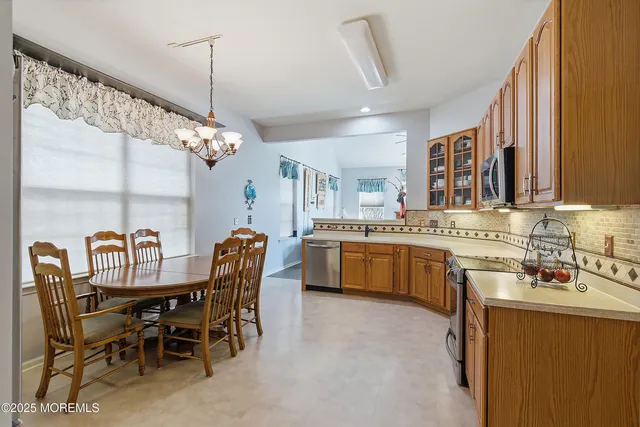 a kitchen with stainless steel appliances granite countertop a stove top oven a sink dishwasher a dining table and chairs with wooden floor