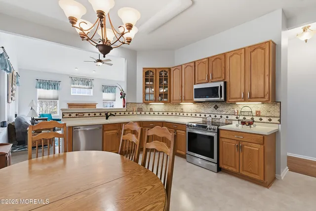 a kitchen with a refrigerator a stove a sink dishwasher a dining table and chairs with wooden floor