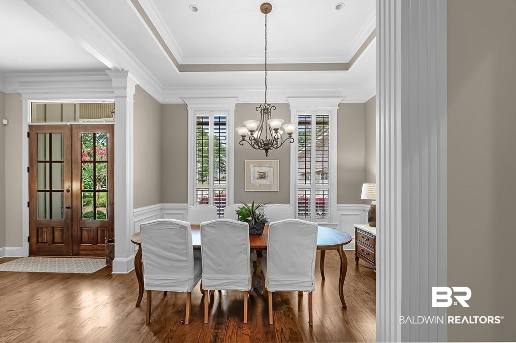 30014 Dolive Ridge Daphne, AL 36527 - Photo 17 of 57 Dining area featuring a tray ceiling, ornamental molding, an inviting chandelier, and wood-type flooring