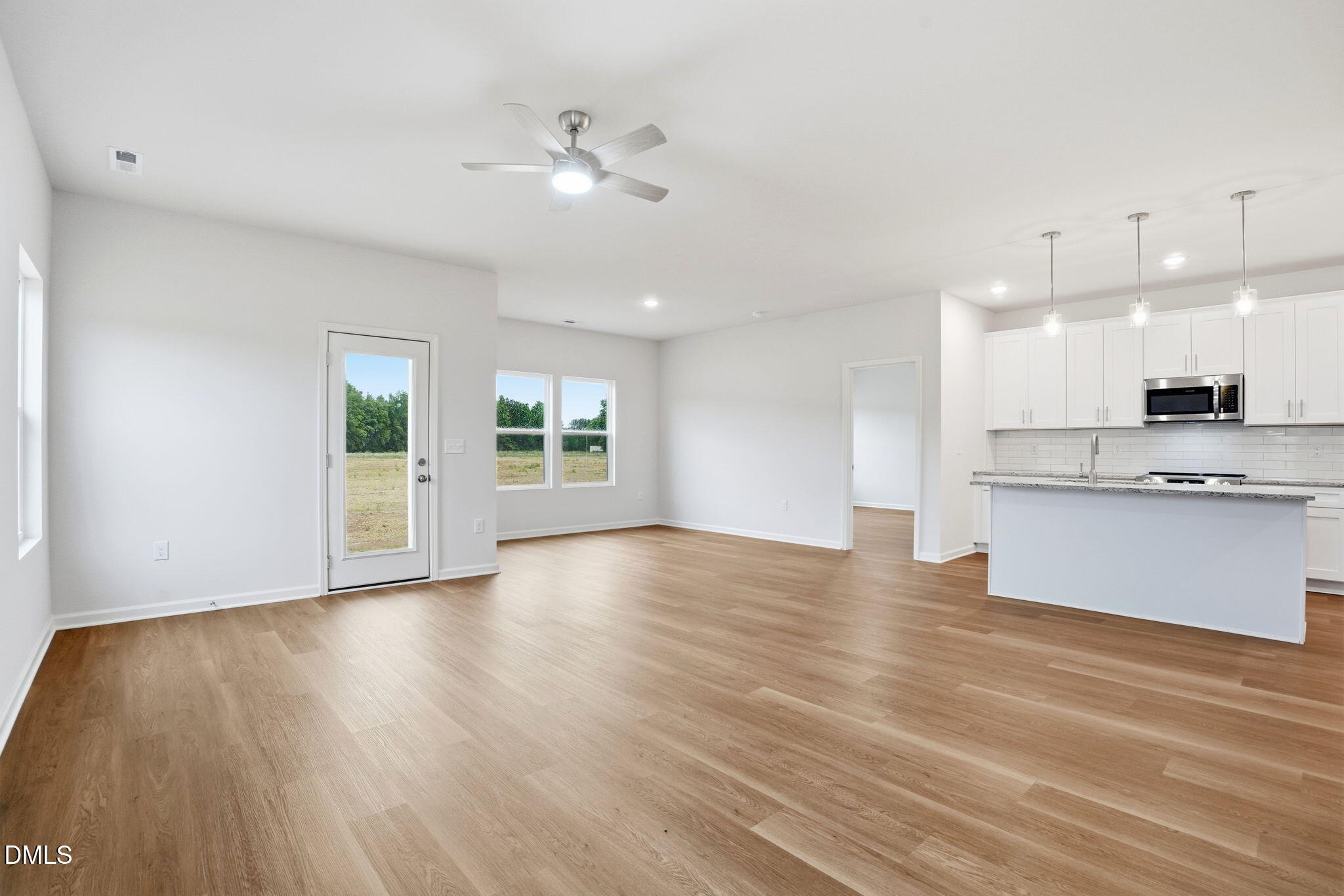 9019 Phoenix Court Spring Hope, NC 27882 - Photo 18 of 34 a view of an empty room and kitchen with wooden floor and kitchen view