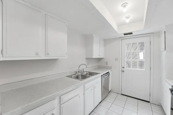 a kitchen with white cabinets and sink