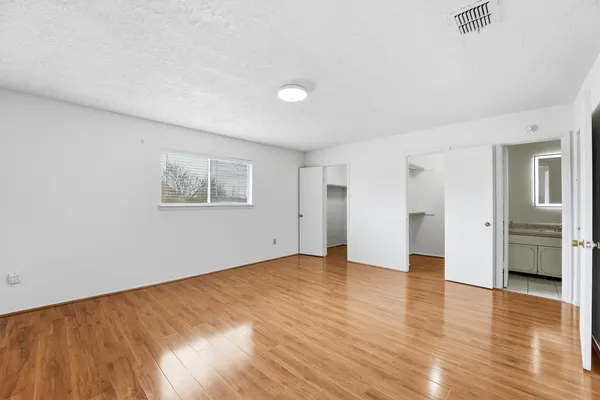 a view of an empty room with a window and wooden floor