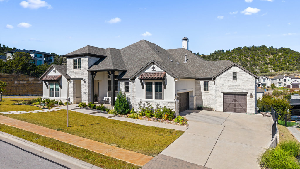 199 Colca Cove Austin, TX 78738 - Photo 1 of 1 French country inspired facade featuring stone siding, concrete driveway, roof with shingles, and a chimney