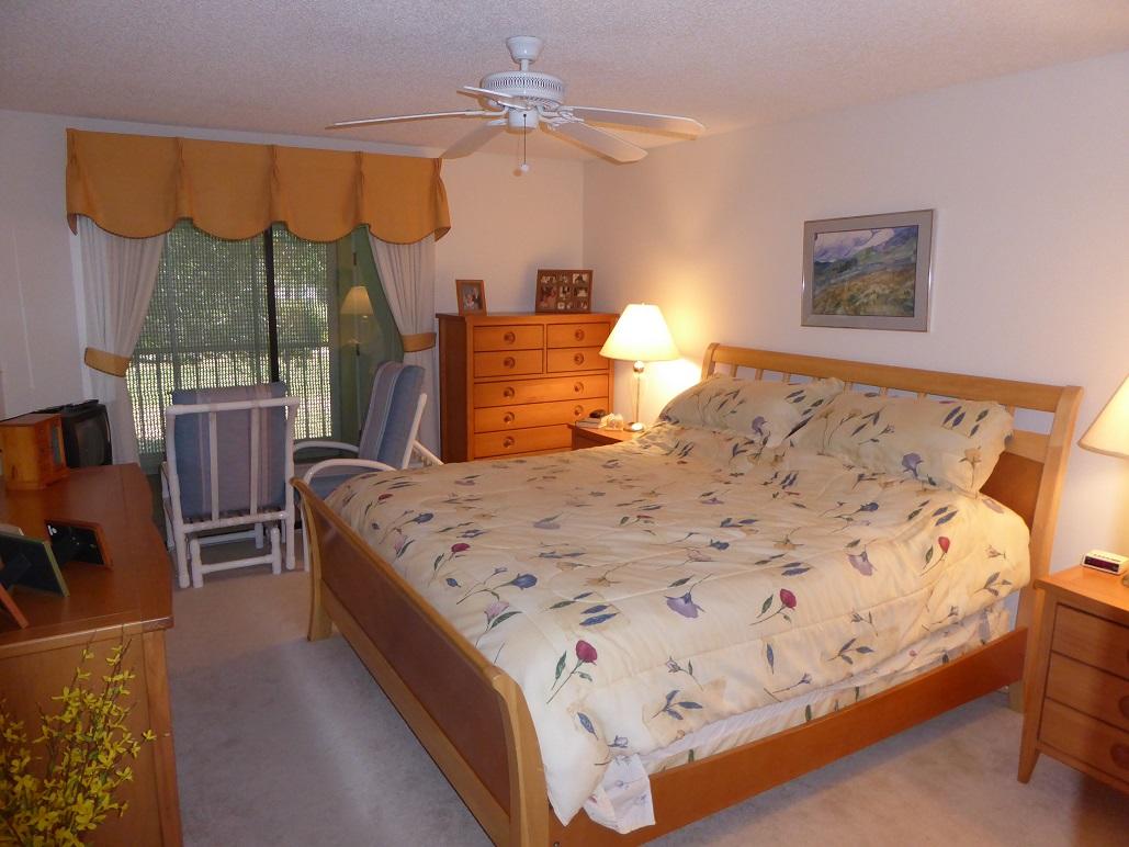 602 Pinecrest Circle, Unit B Jupiter, FL 33458 - Photo 14 of 19 a bed sitting in a bedroom next to a window with lamp