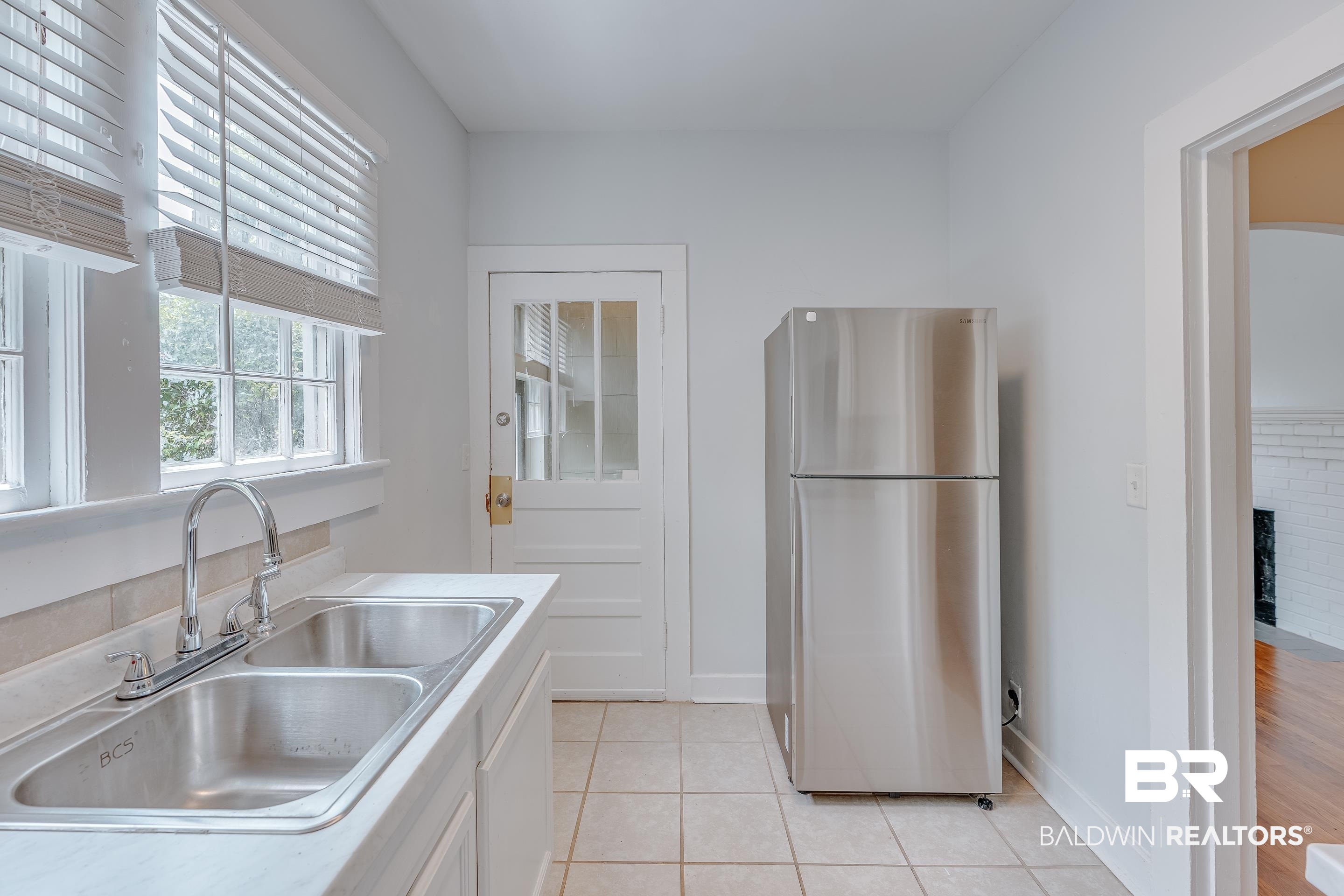 1852 Old Shell Road Mobile, AL 36607 - Photo 11 of 26 Kitchen with freestanding refrigerator, light tile patterned flooring, light countertops, a fireplace, and white cabinetry