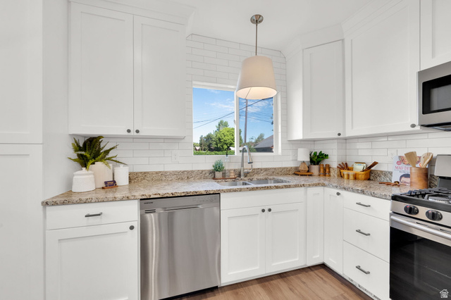 446 South 300 East Provo, UT 84606 - Photo 14 of 32 Modern kitchen featuring white shaker cabinetry, granite countertops, subway tile backsplash, stainless steel appliances, and wood-finish flooring