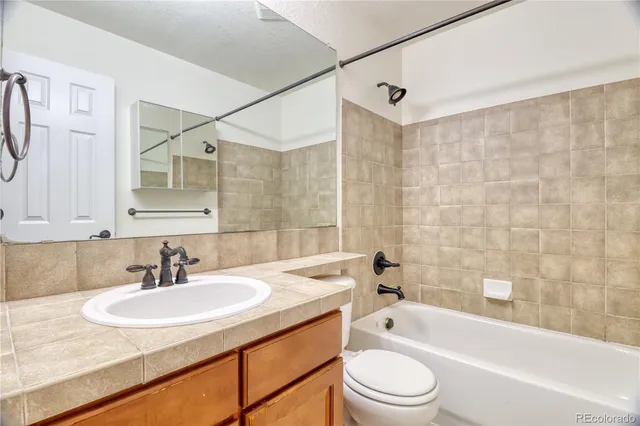 a bathroom with a granite countertop sink a toilet a mirror a bathtub and shower