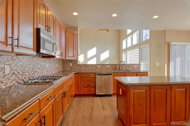 a kitchen with stainless steel appliances granite countertop wooden cabinets a oven and granite counter tops