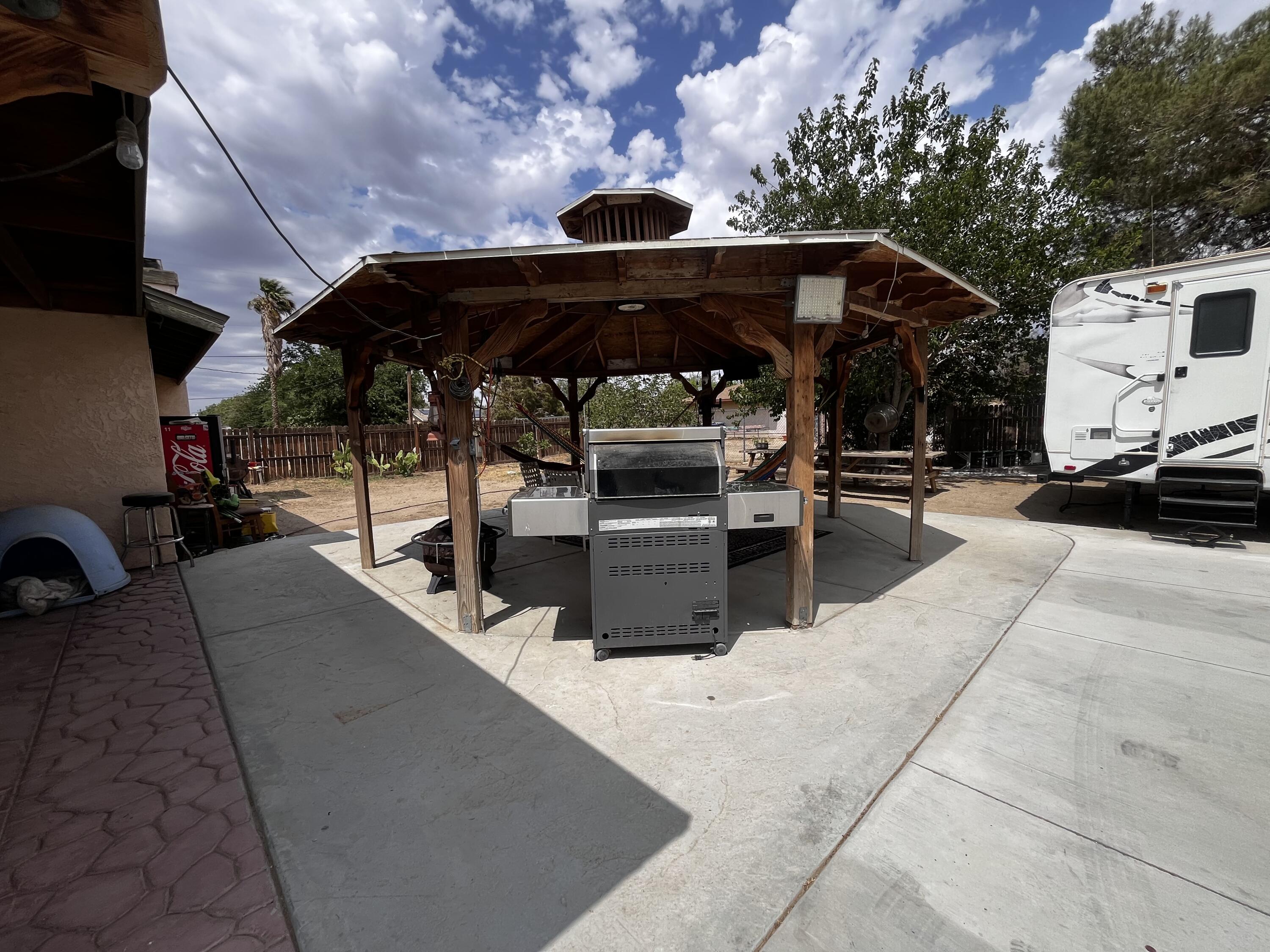 10306 East Ave R 10 Littlerock, CA 93543 - Photo 3 of 7 a view of a patio with table and chairs under an umbrella with a barbeque