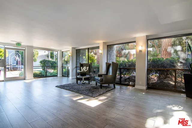 a living room with furniture large windows and wooden floor