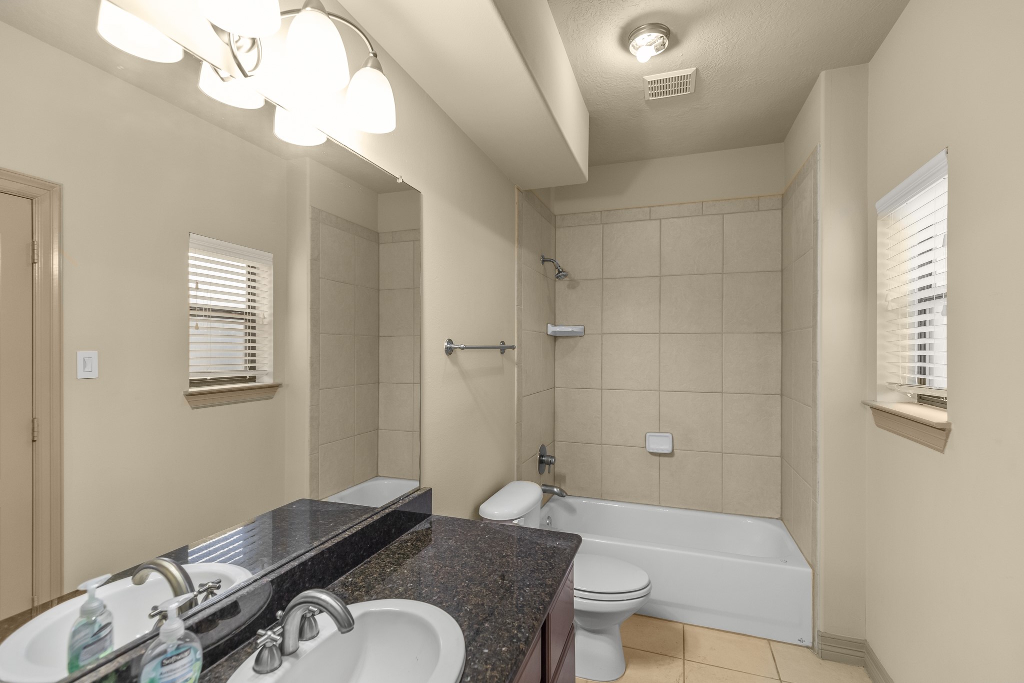 1607 Bass Street, Unit B Houston, TX 77007 - Photo 11 of 39 a bathroom with a granite countertop sink a toilet a mirror and shower