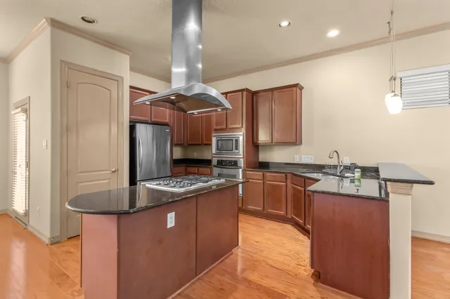 a kitchen with kitchen island granite countertop a sink stainless steel appliances and cabinets
