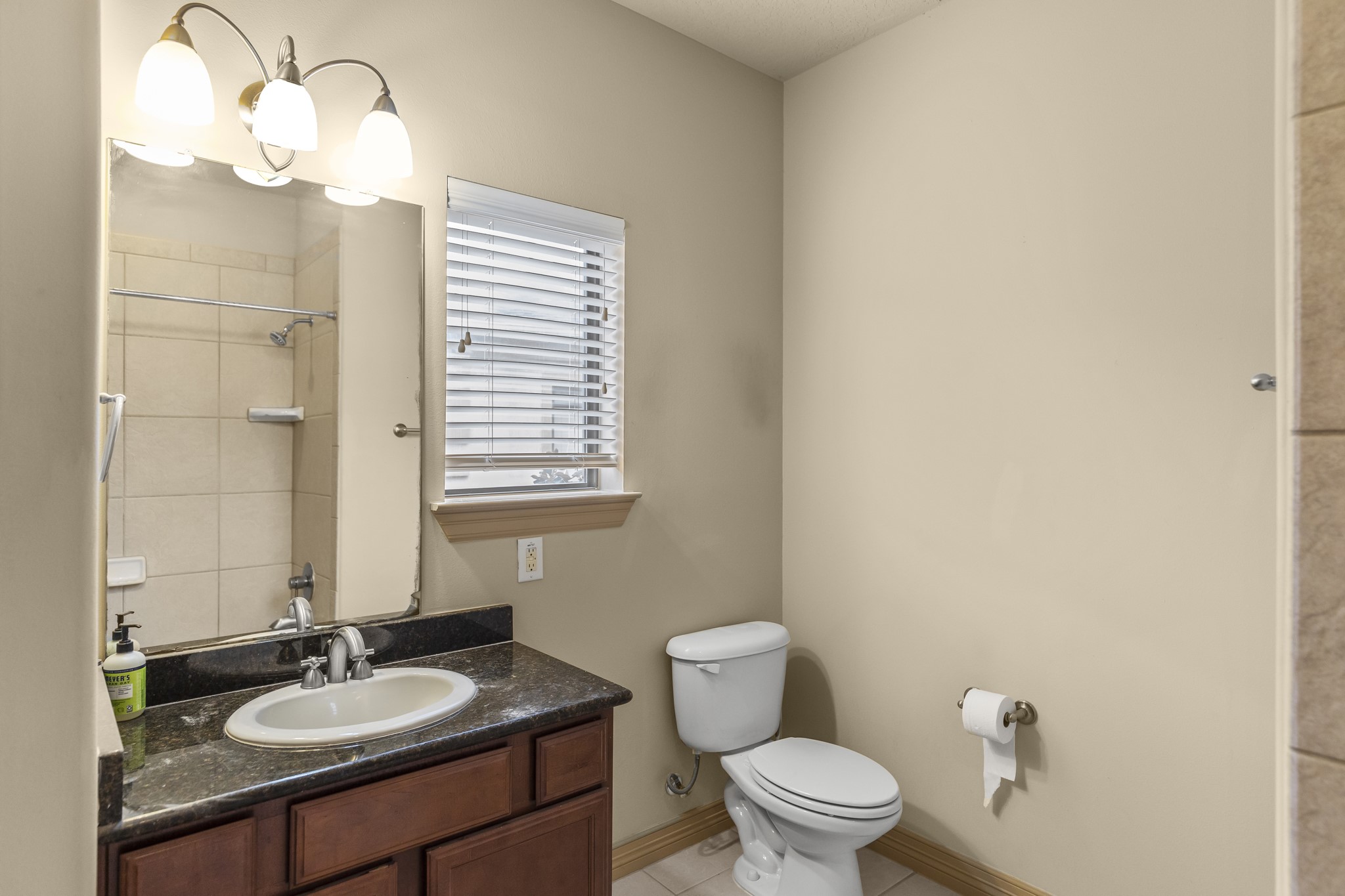 1607 Bass Street, Unit B Houston, TX 77007 - Photo 34 of 39 a bathroom with a granite countertop sink a toilet and a mirror