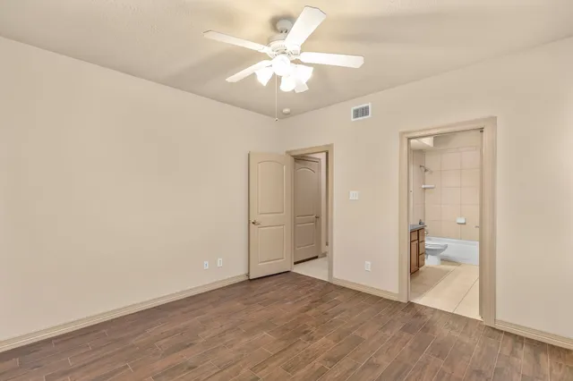 an empty room with wooden floor and a ceiling fan