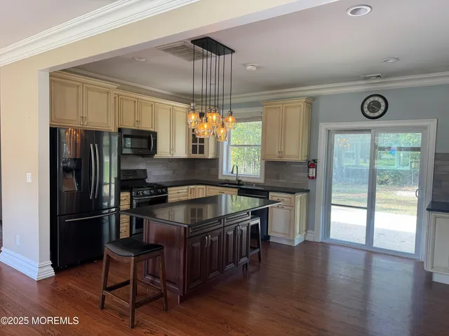 a kitchen with granite countertop a refrigerator a stove a sink and white cabinets