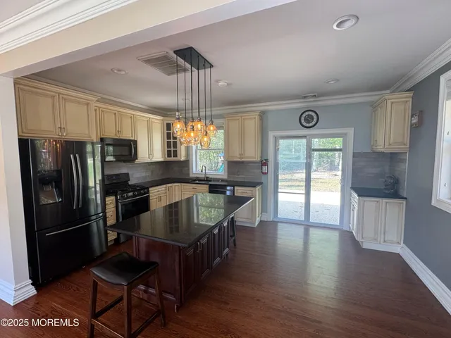a kitchen with stainless steel appliances granite countertop a refrigerator a stove and a wooden floors