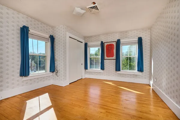 a view of an empty room with window and wooden floor