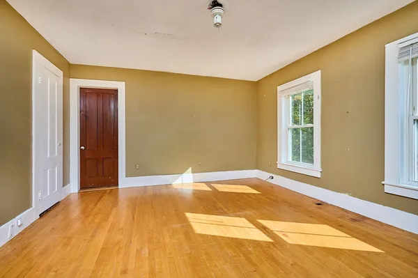 a view of an empty room with window and wooden floor