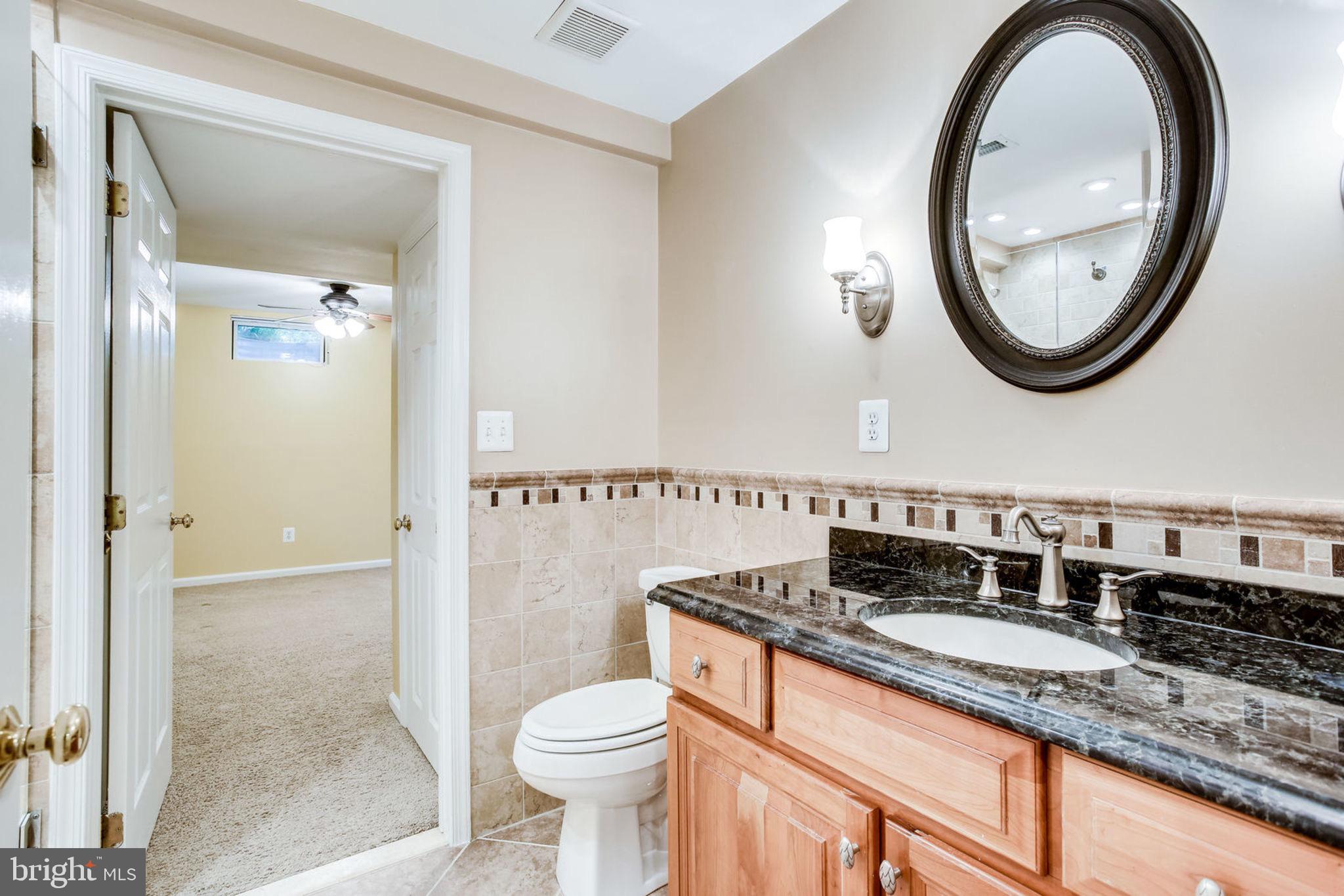 10851 Grovehampton Court Reston, VA 20194 - Photo 34 of 49 a bathroom with a granite countertop toilet a sink and a mirror