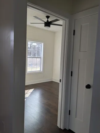 an empty room with wooden floor cabinet and windows