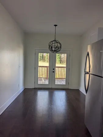 a view of an empty room with wooden floor and fan