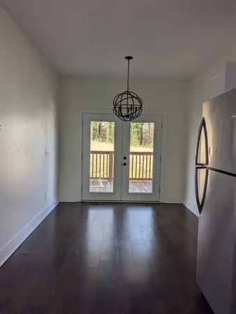 a view of an empty room with window and wooden floor
