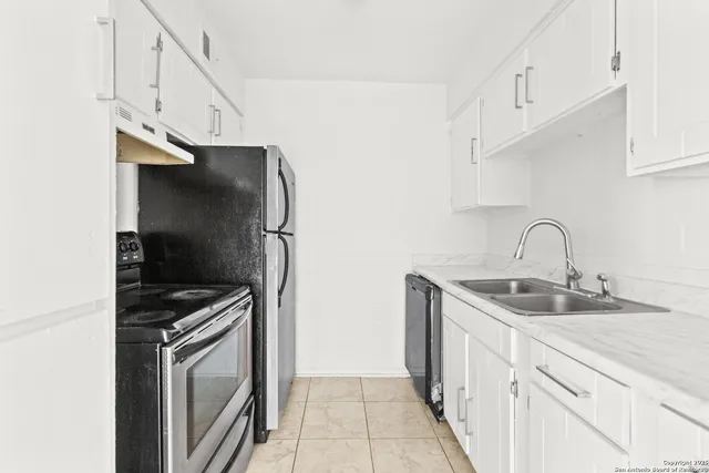 a kitchen with white cabinets and sink