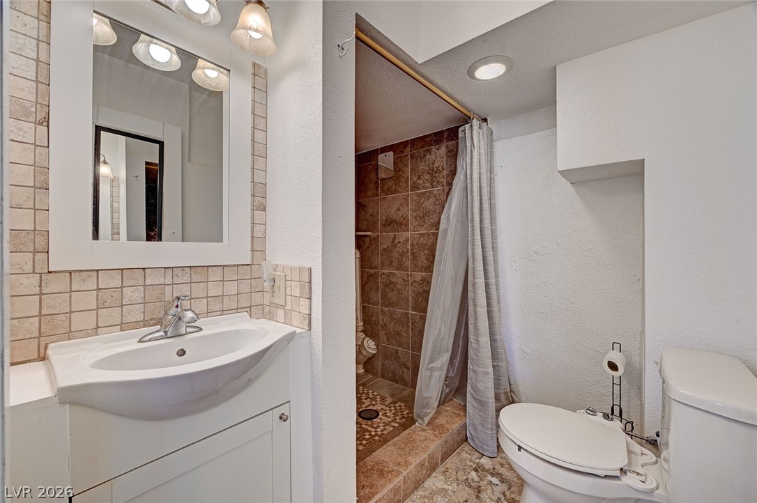 629 L Avenue Boulder City, NV 89005 - Photo 38 of 46 Bathroom featuring vanity, a stall shower, decorative backsplash, and a textured wall