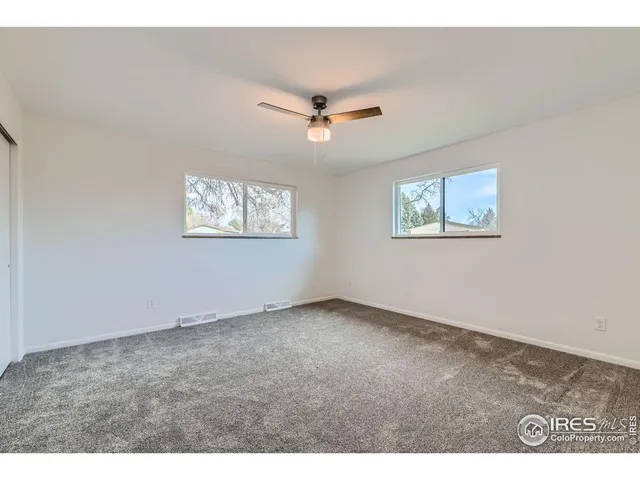 an empty room with windows and ceiling fan