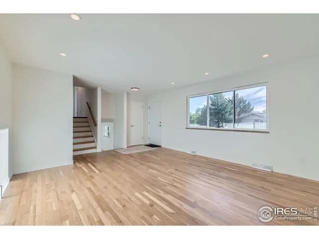 a view of an empty room with wooden floor and stairs