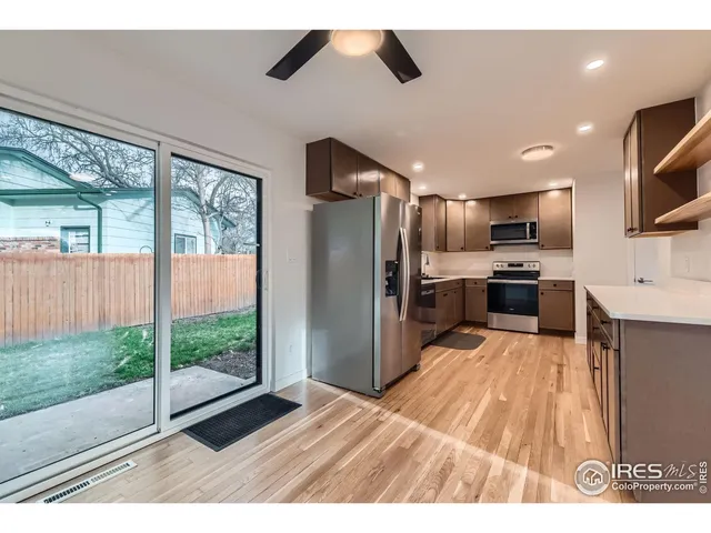 a kitchen with stainless steel appliances kitchen island granite countertop a refrigerator oven a sink and a large window