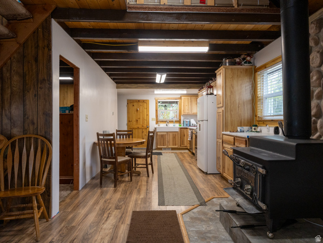 5082 Pine Crest Road Evanston, UT 82930 - Photo 11 of 25 Open-concept kitchen and dining area featuring wood-finish flooring, exposed ceiling beams, and a built-in wood-burning stove