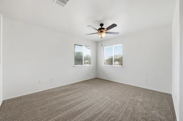 an empty room with a window and a fan