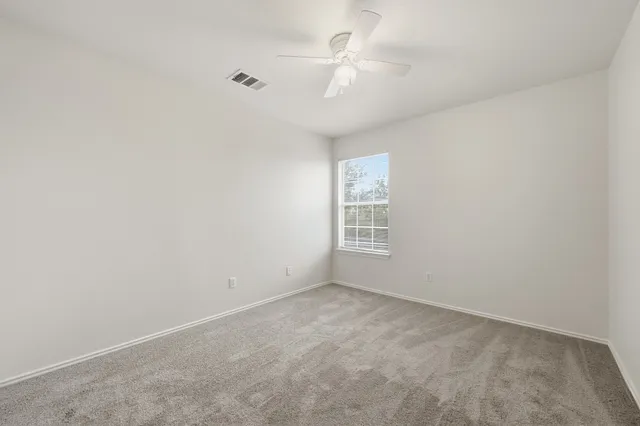 an empty room with windows and fan