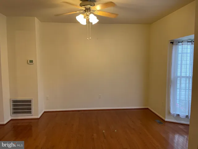 an empty room with wooden floor chandelier fan and windows