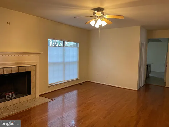 an empty room with wooden floor a ceiling fan and a fireplace