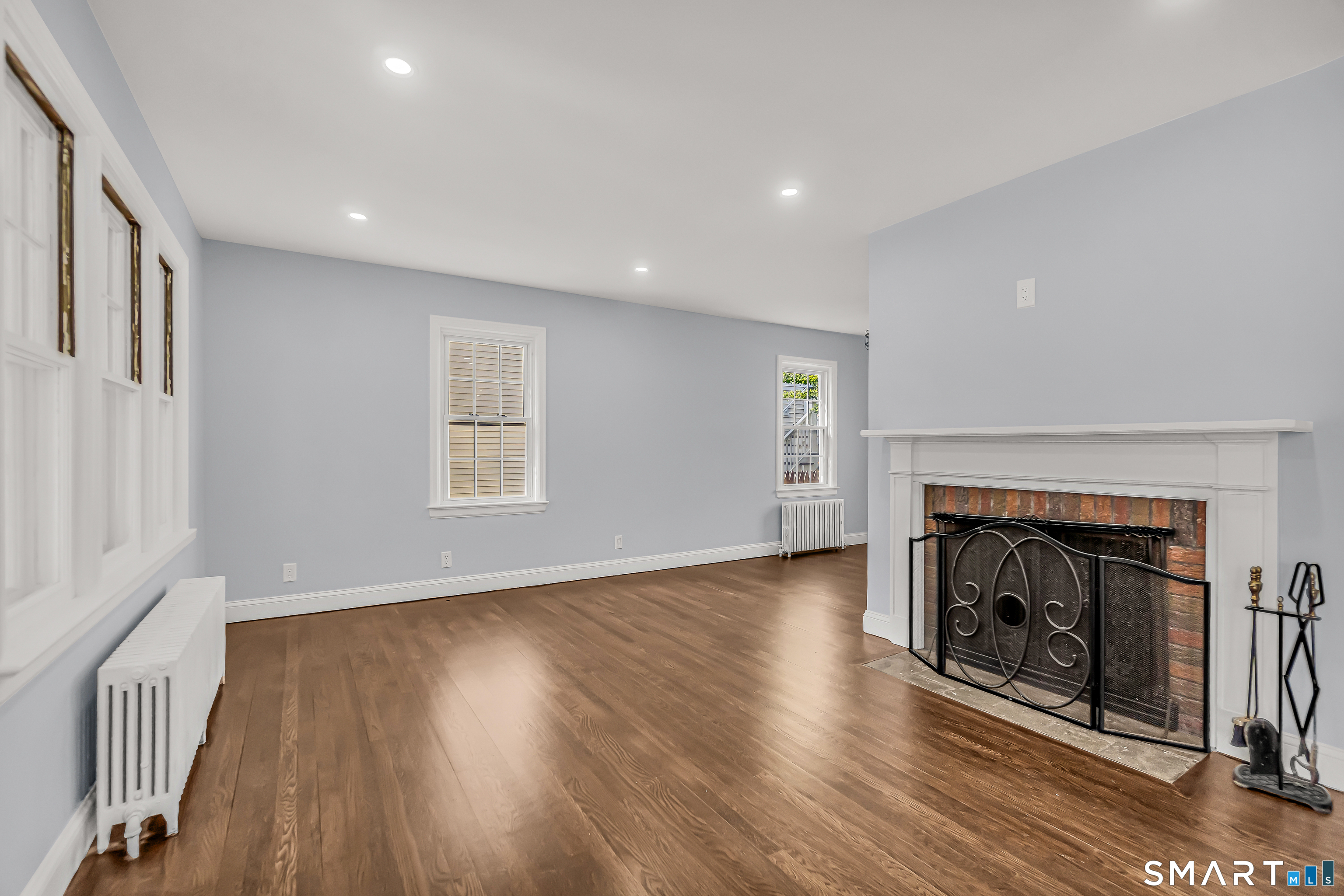1770 Stratfield Road Fairfield, CT 06825 - Photo 10 of 40 an empty room with wooden floor fireplace and windows