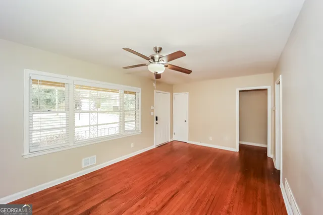 a view of an empty room with wooden floor and a window