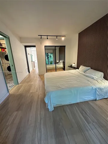 a bedroom with a bed a mirror on dresser and a wooden floor