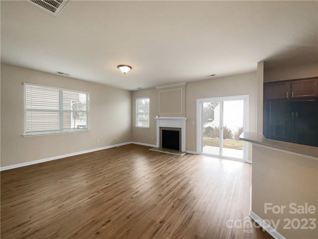 10775 Traders Court Davidson, NC 28036 - Photo 11 of 28 an empty room with wooden floor fireplace and windows