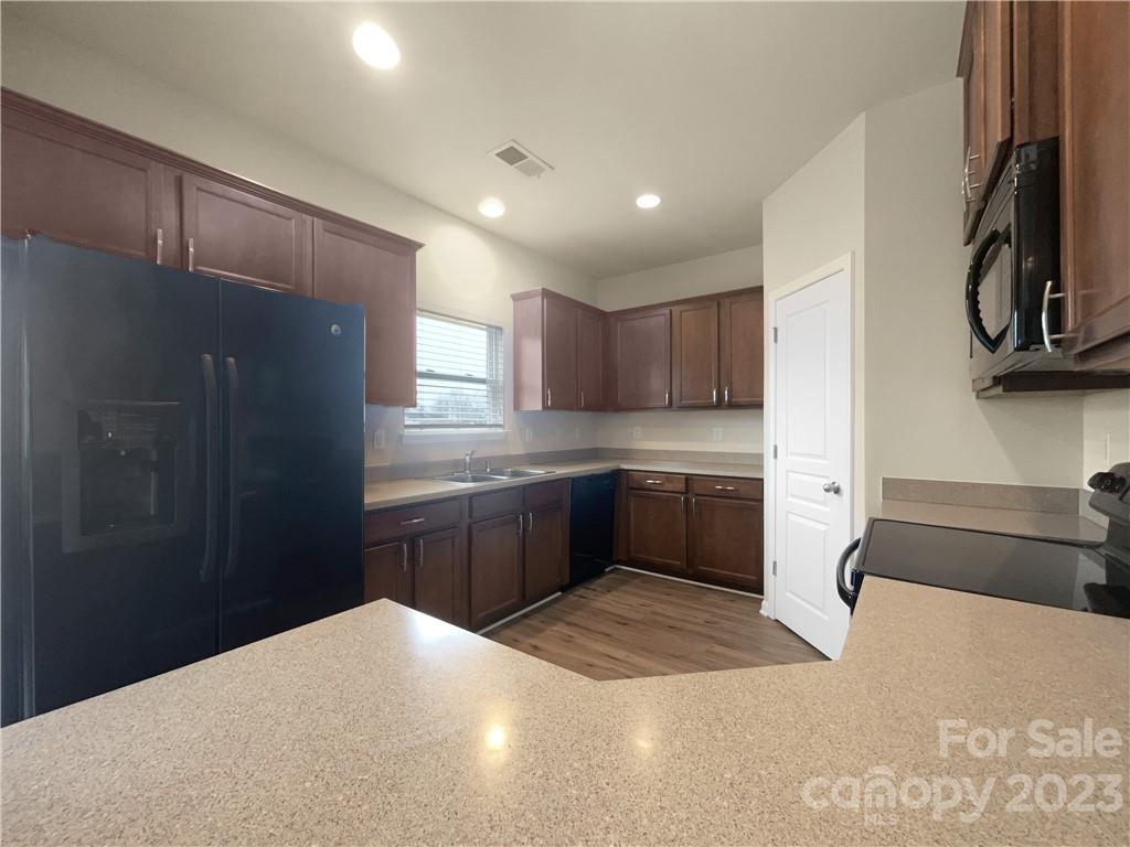 10775 Traders Court Davidson, NC 28036 - Photo 6 of 28 a kitchen with granite countertop a refrigerator and a stove top oven
