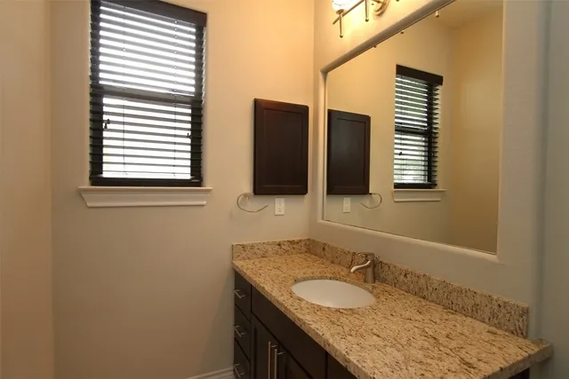 a bathroom with a granite countertop sink and mirror
