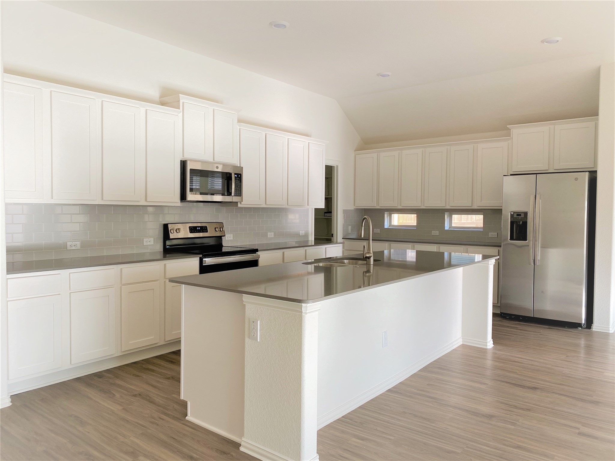 1309 Terrace View Georgetown, TX 78628 - Photo 6 of 36 A contemporary kitchen showcasing ample white cabinetry, sleek countertops, and a functional island with integrated sink.