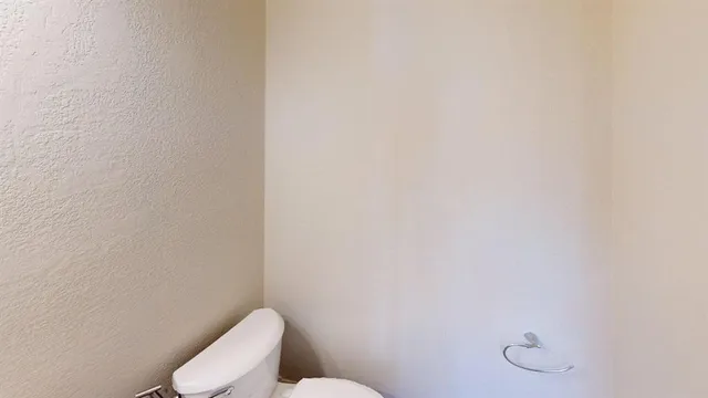 a white toilet sitting next to a white wall