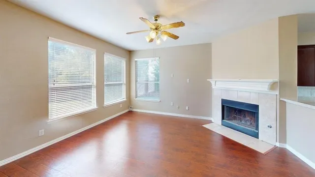 a view of an empty room with wooden floor fireplace and a window