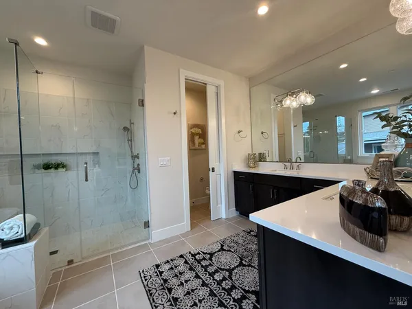a bathroom with a sink a toilet a mirror and shower