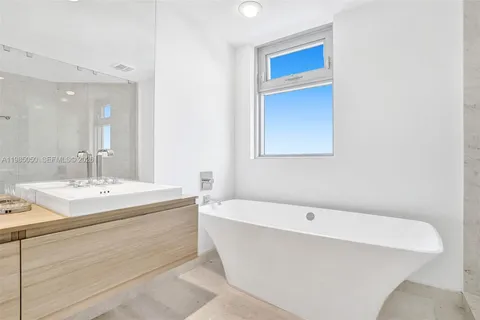 a spacious bathroom with a granite countertop sink a mirror a bathtub and shower