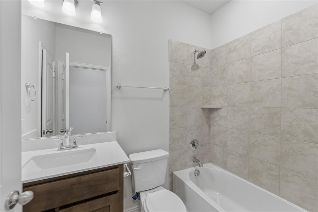 3504 Helena Street Gainesville, TX 76240 - Photo 10 of 19 Modern bathroom featuring a wood-finish vanity with a white countertop and integrated sink, chrome faucet, and rectangular mirror
